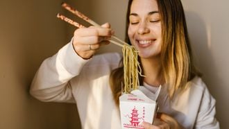 Meisje eet met stokjes gerecht uit Koreaanse keuken