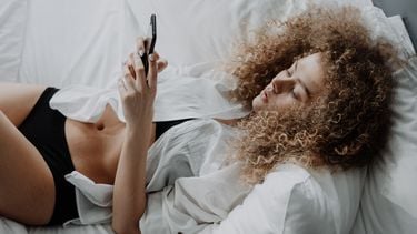 sexting / vrouw ligt met telefoon in bed