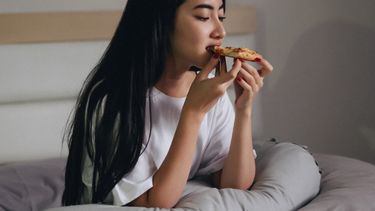 in bed eten / meisje eet pizza in bed
