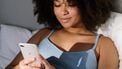sexting / meisje ligt met haar telefoon in bed foto's verwijderen telefoon app