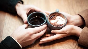 stelletje houdt handen vast en kop koffie (deze 5 netflix vrije date-ideeën wil je proberen)