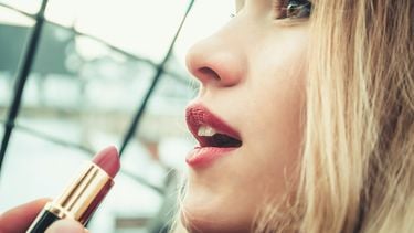 meisje doet lipstick op (Deze liquid lipstick kleuren passen het beste bij jouw huidskleur)