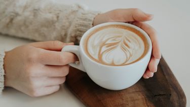 Vrouw houdt koffie in mok vast (Dit instagram account wil je volgen voor koffie recepten)