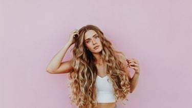 meisje blond haar voor roze muur (Waarom je geen kokosolie moet gebruiken in je haar)